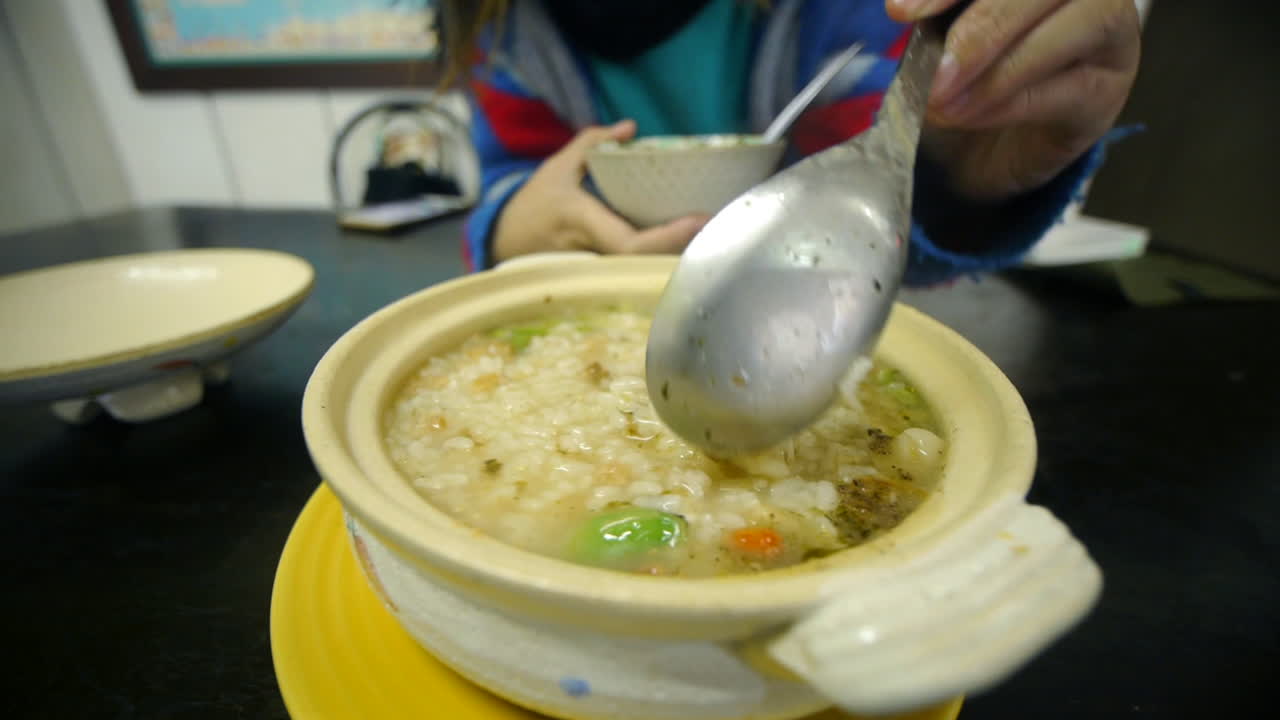 Delicious rice and vegetable kanji porridge soup being stirred with ...