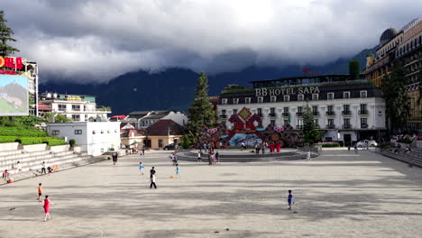 kids playing soccer on a concrete surface playground, sapa town under rainy and cloudy sky