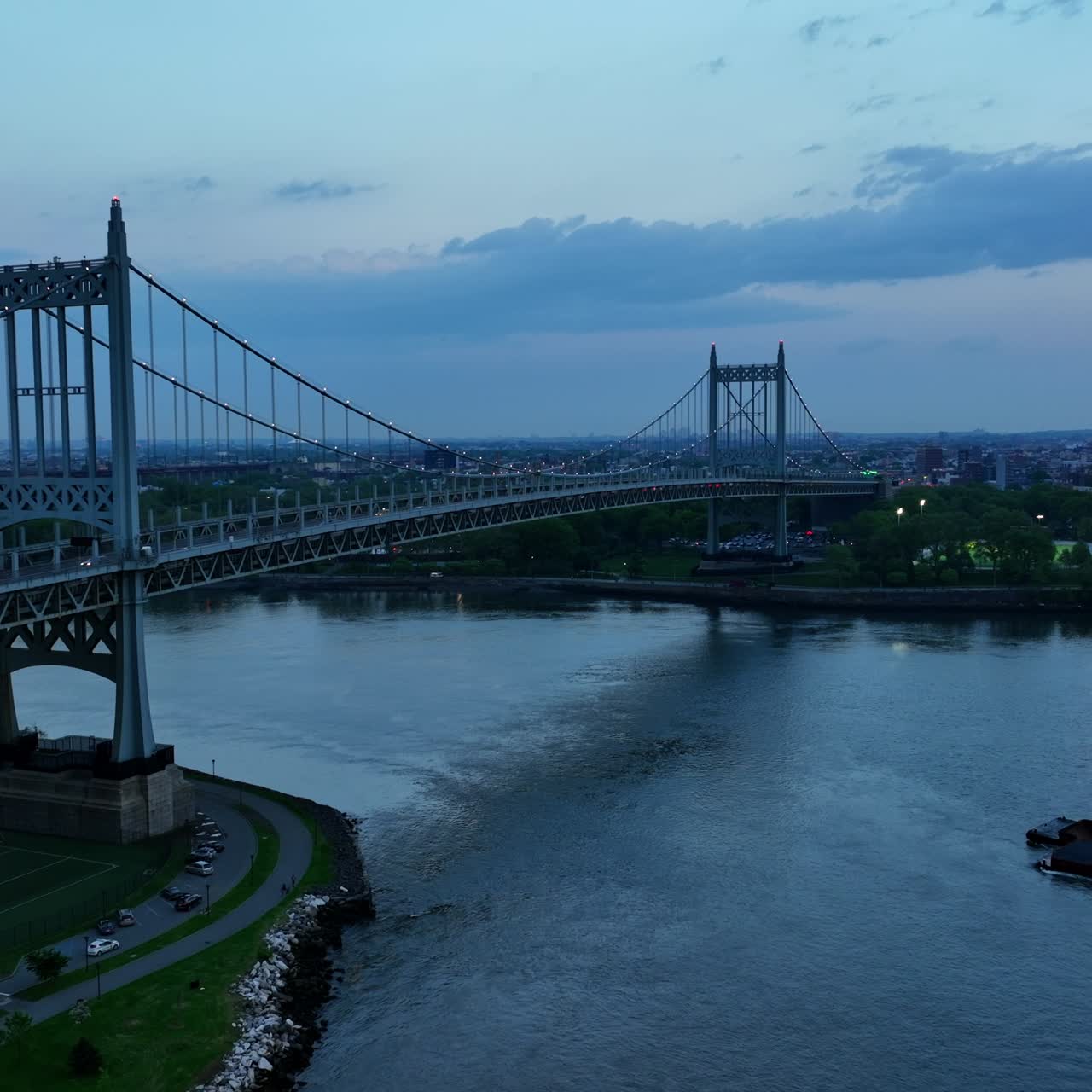 Ferry boat floating by East River. Beautiful Triborough Bridge with transport going by and under it. Evening time in New York