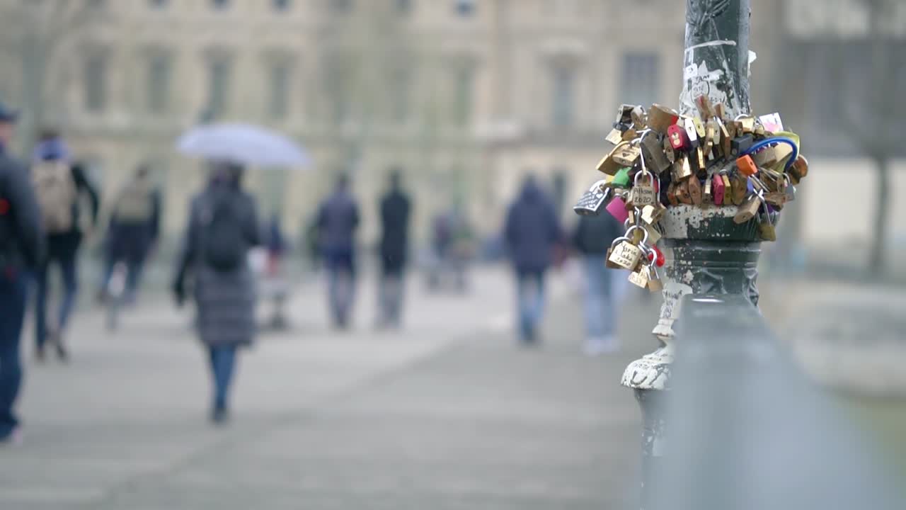 Slow motion clip of love locks on a pole in paris city centre with people walking out of focus blur in the background