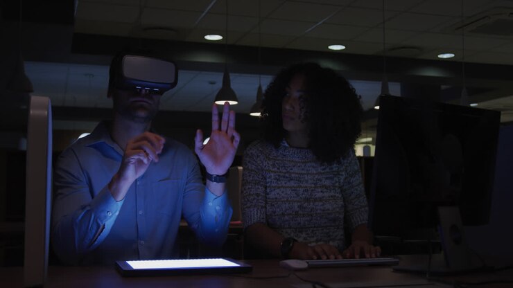 Unge forretningsfolk arbejder med en digital tablet og bruger VR-hjelm på et moderne kontor.