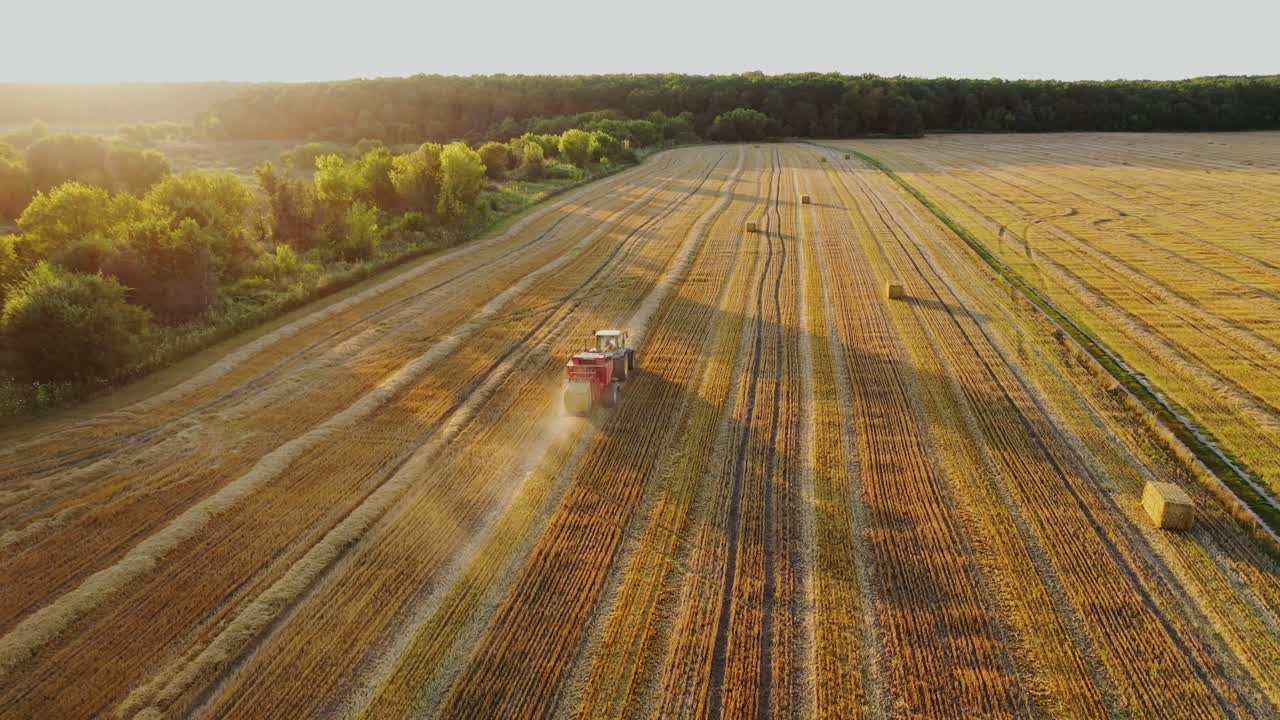 Tractor collecting straw bales. Tractor collecting hay bales in the fields