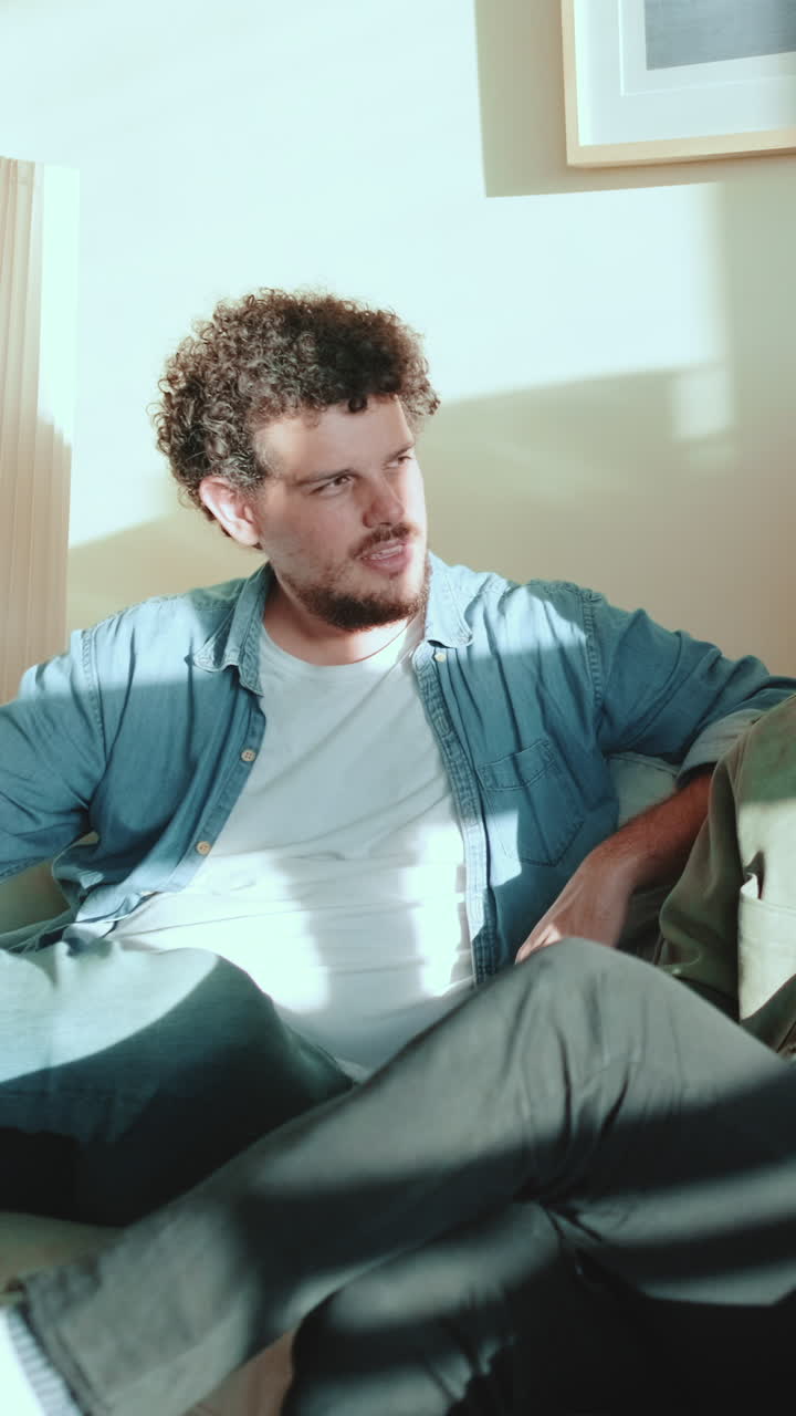Man with curly hair sitting on a couch
