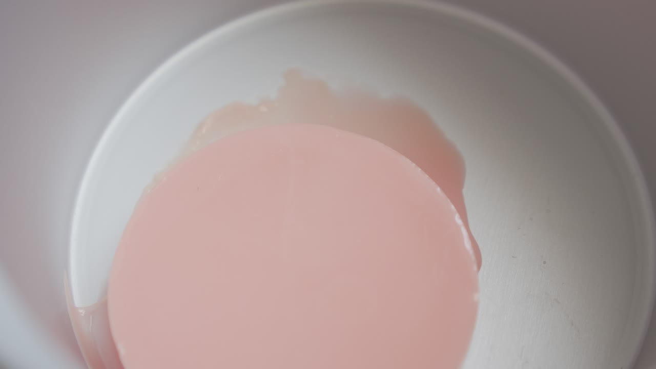 Melting of pink hard wax cake in electric warmer 4K video