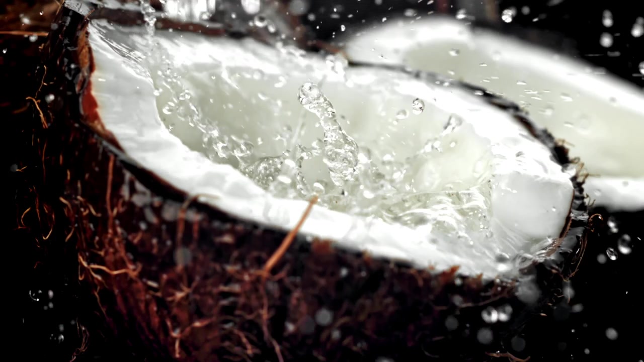 Refreshing Water Splashing into a Halved Coconut in Slow Motion
