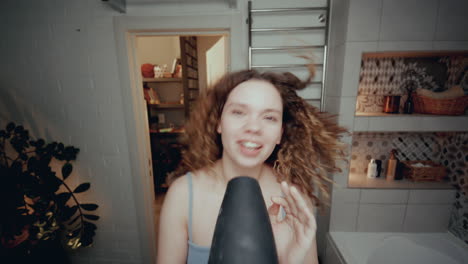 chica emocionada cantando en el baño con secador de pelo en lugar de micrófono
