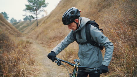 athletischer männlicher radfahrer, der mit dem mountainbike auf dem hügel die straße hinunter in der mitte des tals fährt