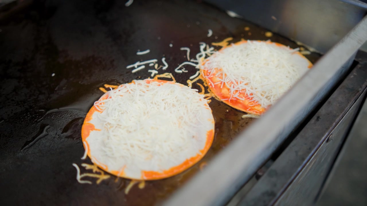 Traditionelle madlavningsoptagelser, der viser tortillas med ost, der tilberedes på en flad grill under forberedelsen af friske håndlavede majstortillas.