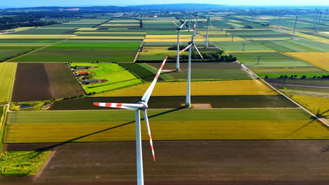 turbines produce energy in fields. wind turbines rotate above vibrant fields, harnessing wind energy while casting long shadows on the landscape