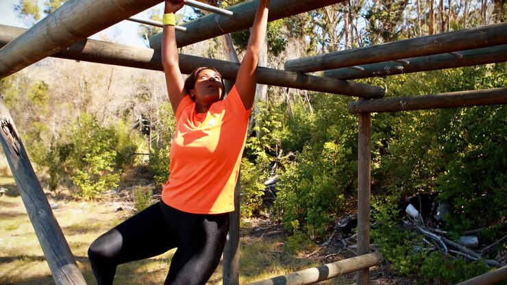 Determined woman exercising on monkey bar during obstacle course