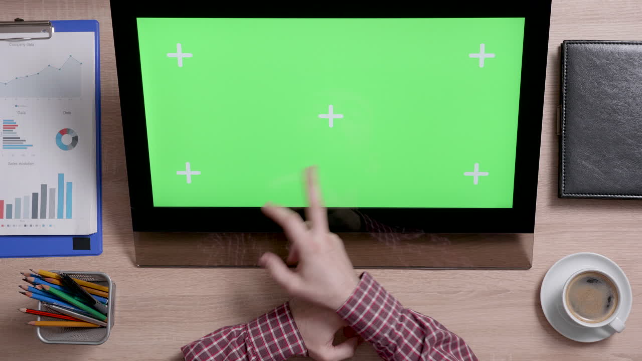 Top view of desk with computer and green screen