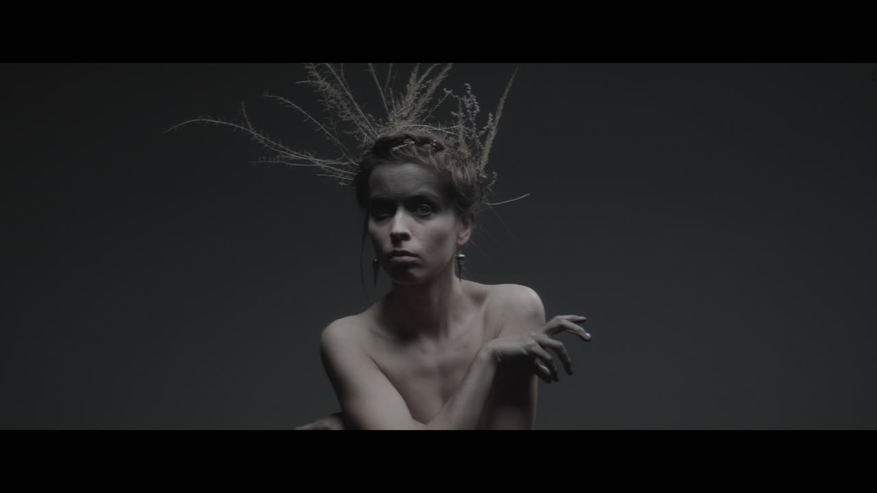 A woman dressed as mother nature moves slowly in a dance-like motion