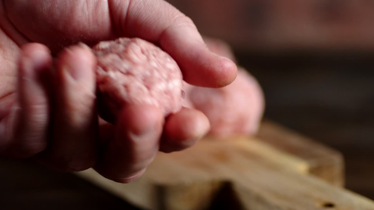 las manos masculinas hacen las albóndigas de carne picada.