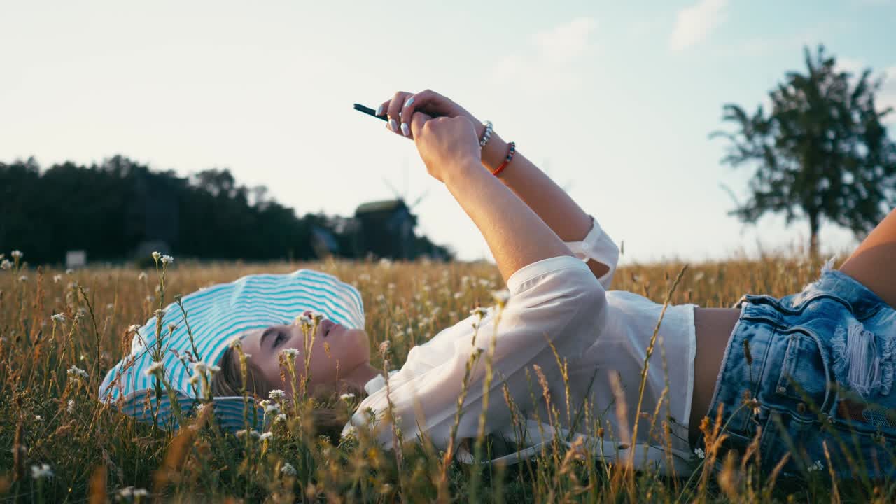 휴대 전화를 사용하는 여름 공원의 여성. 정통한 창의적인