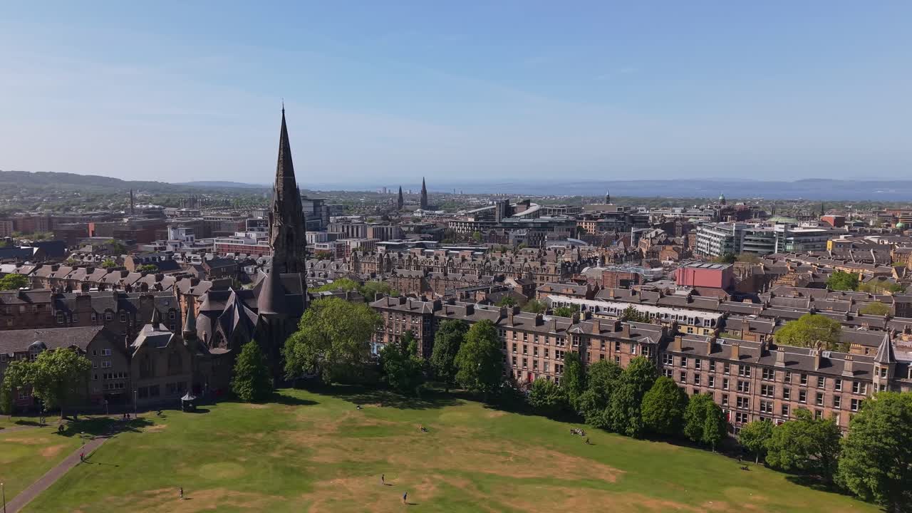 Drone orbits the Barclay Viewforth Church in Edinburgh, gradually revealing the city's diverse skyline and historic charm under a clear sky