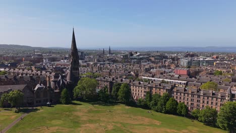 drone orbits the barclay viewforth church in edinburgh, gradually revealing the city's diverse skyline and historic charm under a clear sky