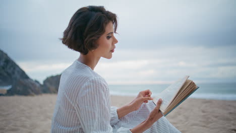 thoughtful woman holding book at sea beach closeup. focused model flipping pages