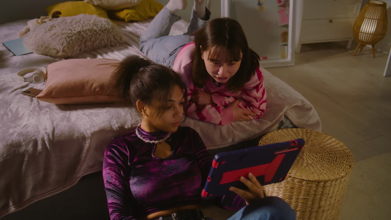 Teenage girls watching tablet together in bedroom