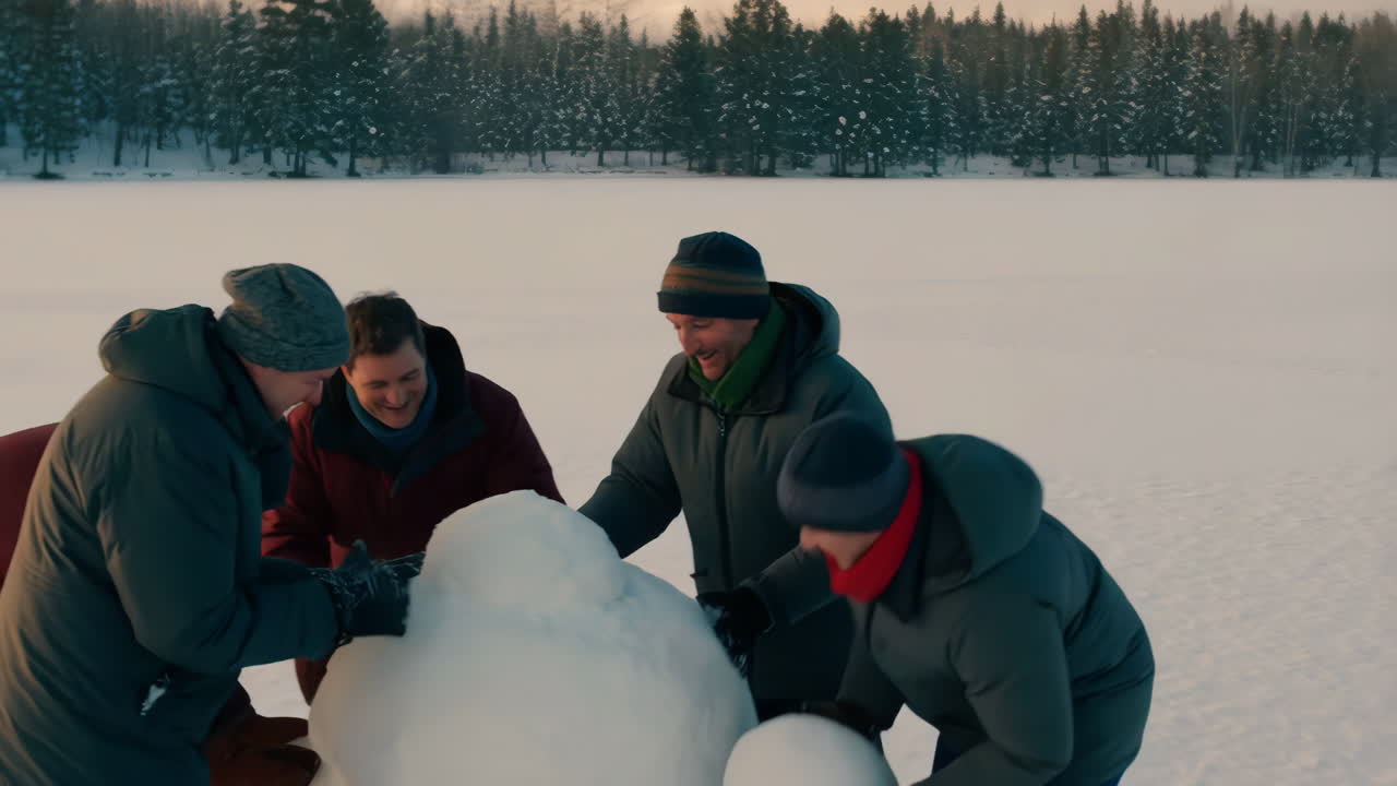 Group of friends building a snowman in winter landscape