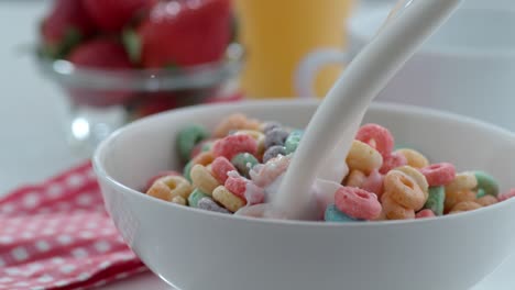 la leche se vierte en un cuenco de cereales en cámara lenta