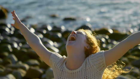 woman standing with arms outstretched in the beach 4k