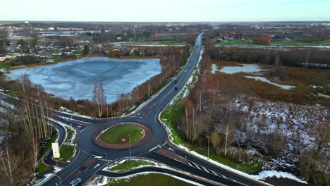 aerial drone top down shot over a road crossing beside a frozen lake on a cold winter day