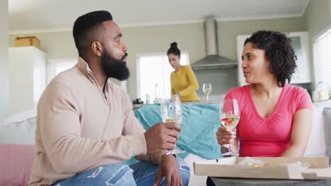 three happy diverse female and male friends toasting with wine at home, in slow motion