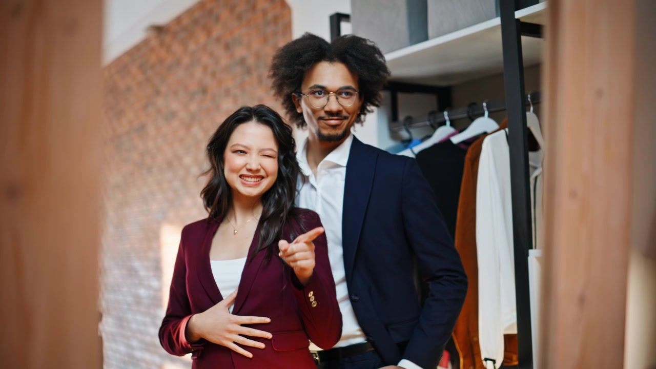 Mulher elegante ajustando o paletó do terno de um homem em loja de roupas. Dupla animada posando