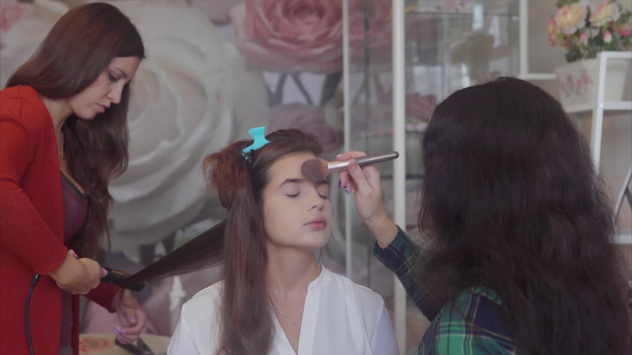 mujer que se hace el cabello y el maquillaje en un salón