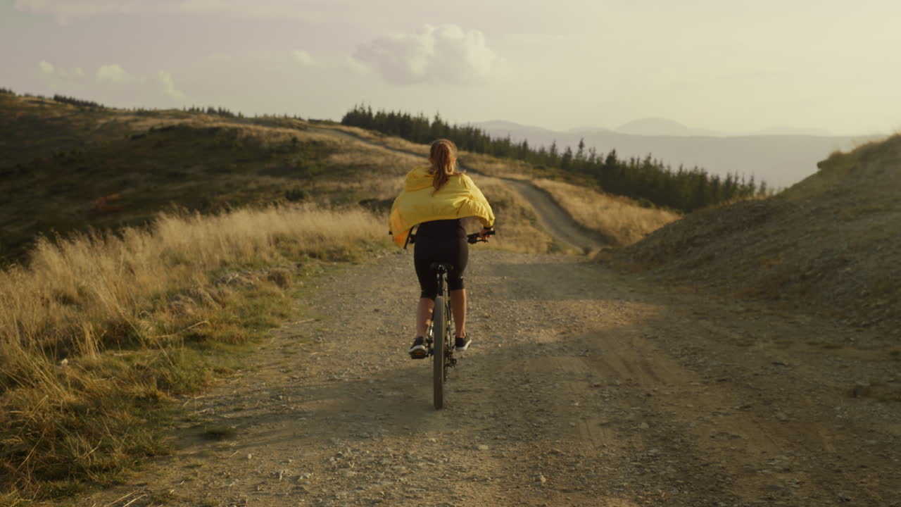 Female cyclist riding bicycle down road. Woman on sport bike training outdoor