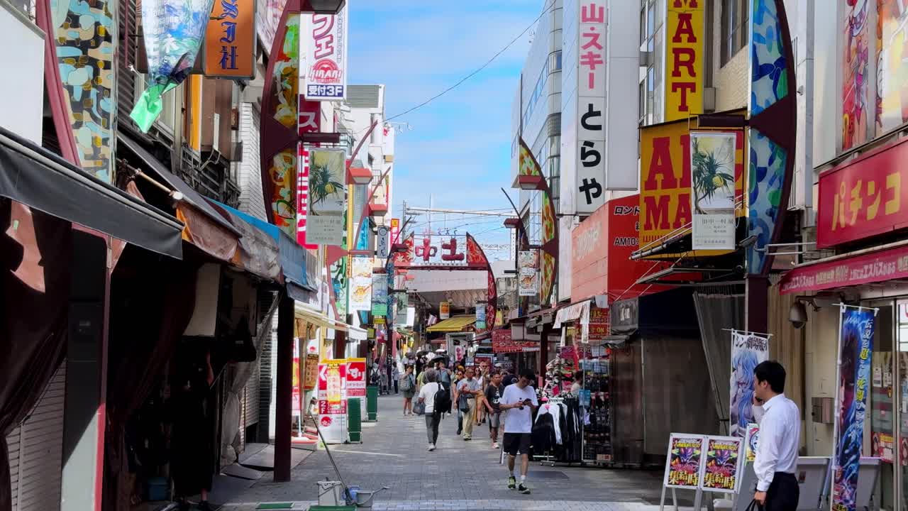 Busy pedestrian street in Japan with colorful signs and shops on a sunny day