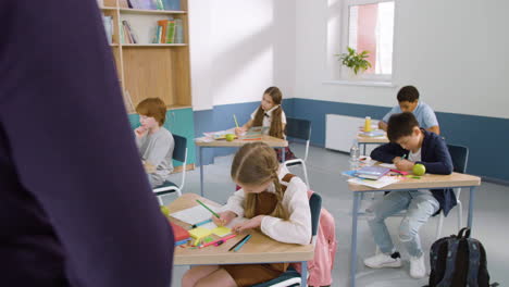 multi-etnische groep kinderen in de klas die in hun notitieboekje schrijven tijdens de engelse les op school