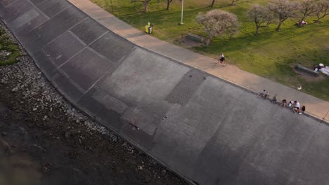 woman cycling along promenade of along rio de la plata river, buenos aires