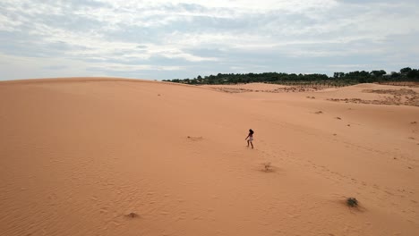 Frau,-Die-An-Einem-Bewölkten-Tag-In-Mui-Ne-Vietnam-Eine-Rote-Wüstensanddünenlandschaft-Hinaufgeht