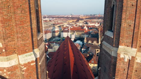 ascending drone shot showing city of munich between two towers of frauenkirche church at sunny day