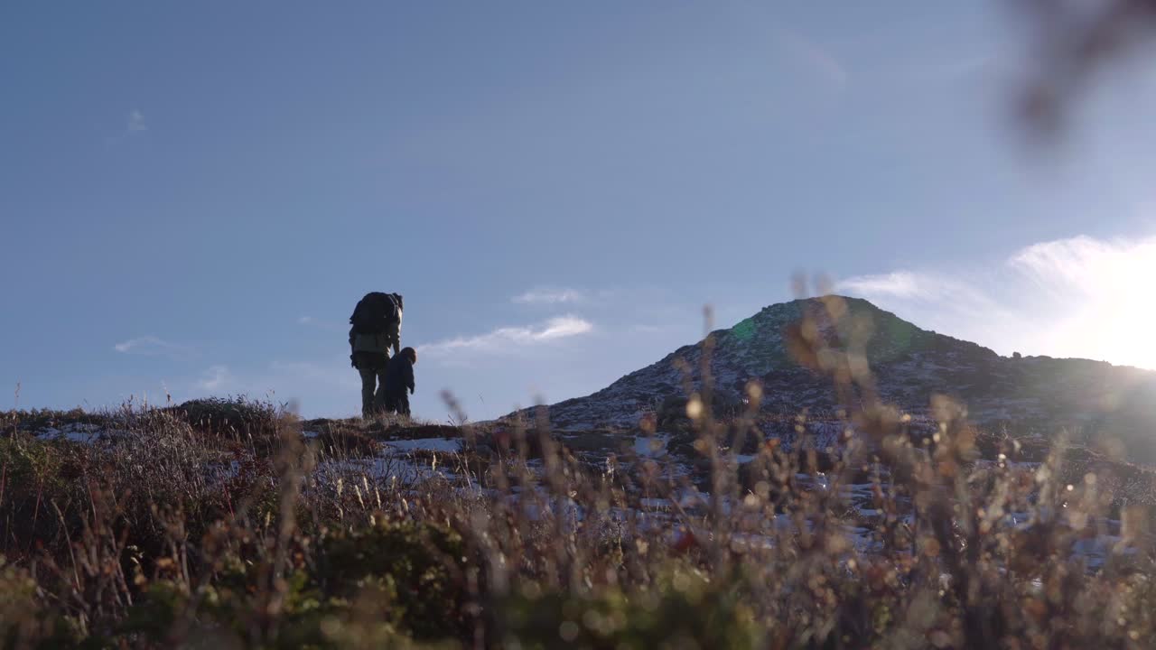 toma cinematográfica de un niño y su abuelo haciendo senderismo en la montaña durante la fresca y soleada mañana de otoño, 2