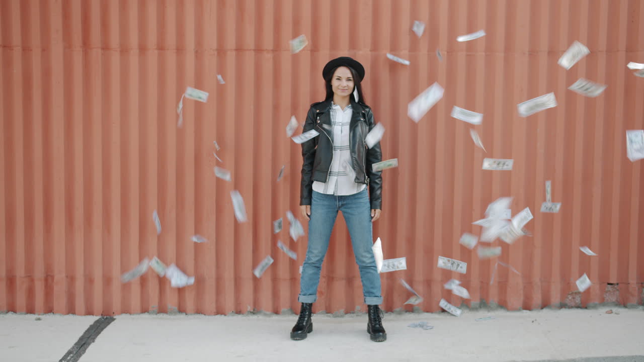 Woman Holding Money in Front of Orange Wall