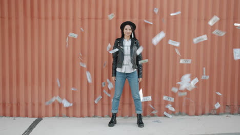 woman holding money in front of orange wall