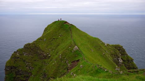 Two-hikers-on-a-cliff's-edge-next-to-the-Atlantic-Ocean-taking-pictures