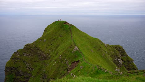 two hikers on a cliff's edge next to the atlantic ocean taking pictures