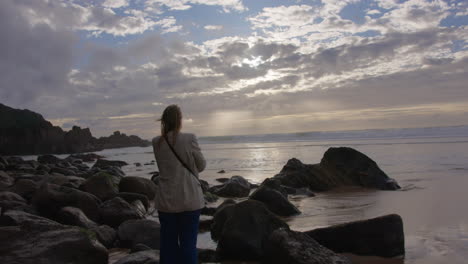 woman contemplating the sunset on a rocky beach