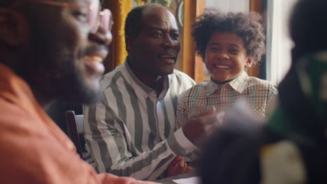 african american boy sitting with dad at family dinner