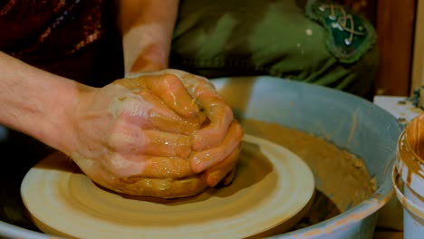 professional male potter working with clay on potter's wheel