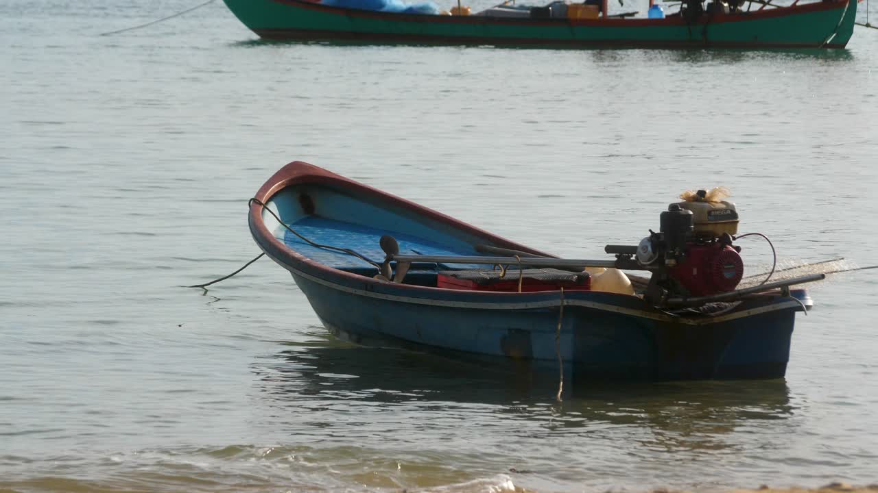 Small fishing boats moored in Gulf of Thailand shore with longtail boat in distance