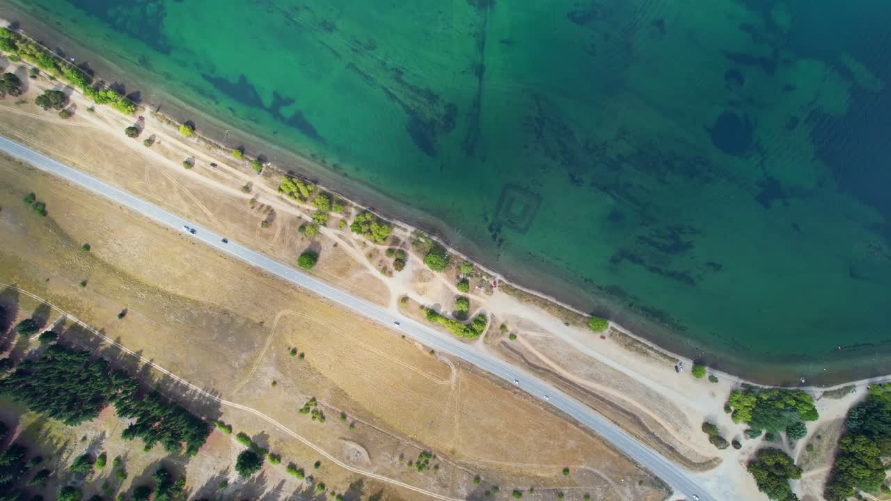 Drone descending down towards rural highway next to Dunstan Lake showing its crystal water in Cromwell, New Zealand