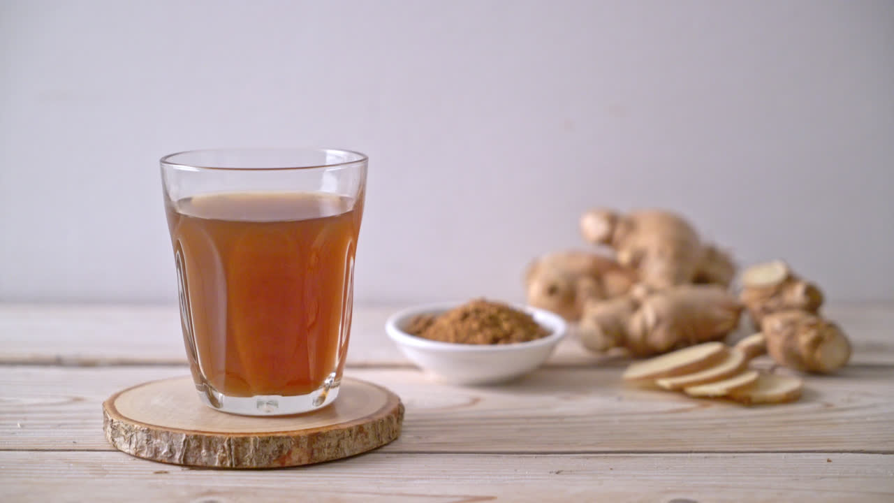vaso de jugo de jengibre dulce y caliente con raíces de jengibre - estilo de bebida saludable