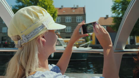 a woman takes pictures of herself against the background of copenhagen's city line sails on a sights