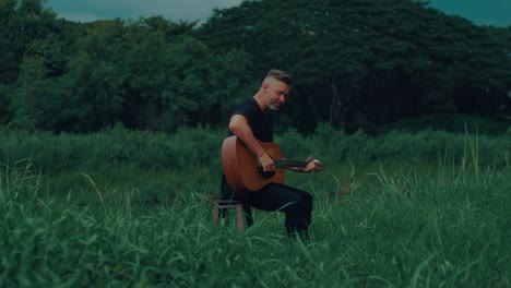 man singing and playing acoustic guitar in a forest