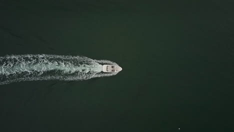 top down aerial footage following a small speedboat cruising on deep blue calm water