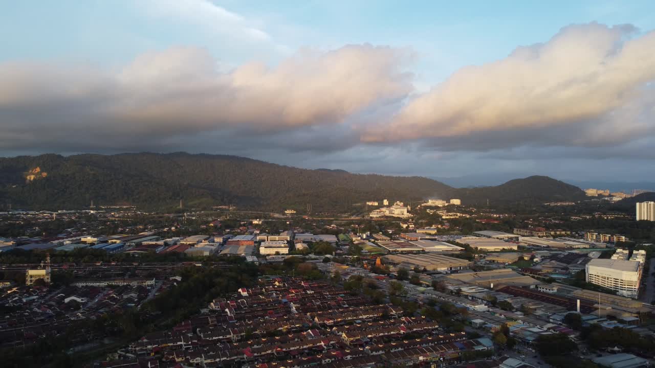 incluye área de vivienda y fábricas durante la puesta del sol y presenta algunos valles de montaña por delante